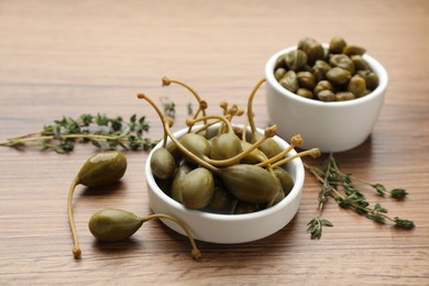 Delicious pickled capers and thyme twigs on wooden table