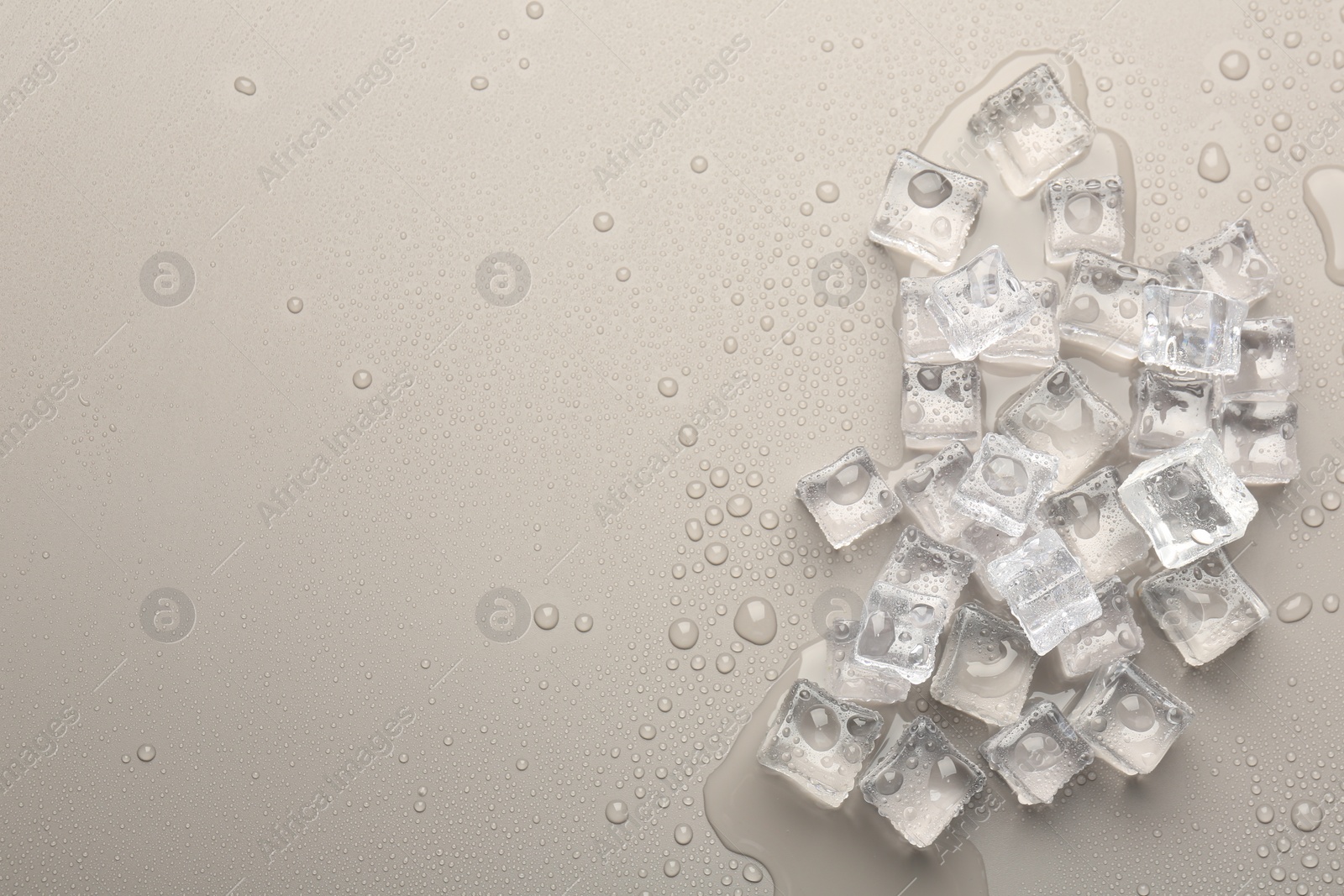 Photo of Melting ice cubes and water drops on light grey background, flat lay. Space for text