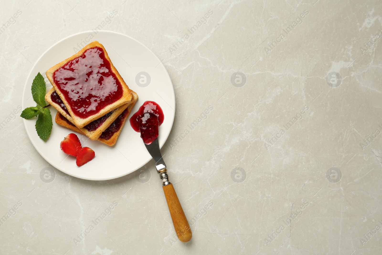 Photo of Toasts served with tasty jam, mint and strawberry on light marble table, top view. Space for text