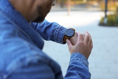 Photo of Man looking at watch outdoors, closeup. Being late concept