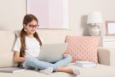 Photo of Girl with laptop and books on sofa at home