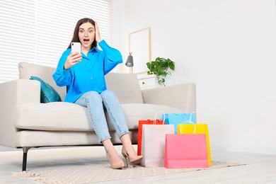 Special Promotion. Emotional woman looking at smartphone on sofa indoors, space for text