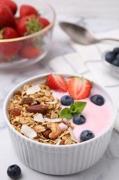 Photo of Tasty granola, yogurt and fresh berries in bowl on white table, closeup. Healthy breakfast
