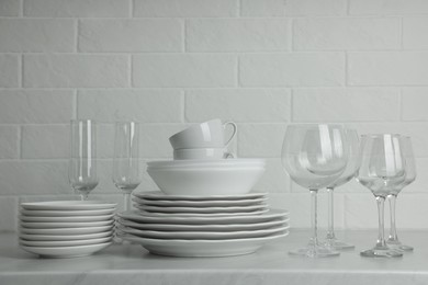Photo of Different clean dishware, cups and glasses on countertop