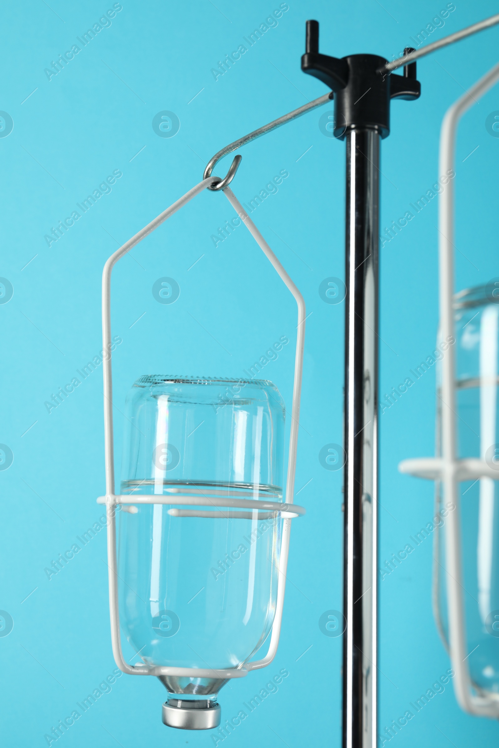Photo of IV infusion set on pole against light blue background, closeup