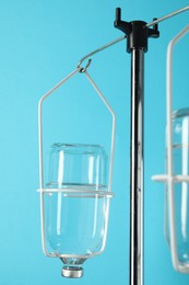 IV infusion set on pole against light blue background, closeup