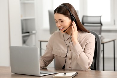 Photo of Hotline operator with headset working on laptop in office