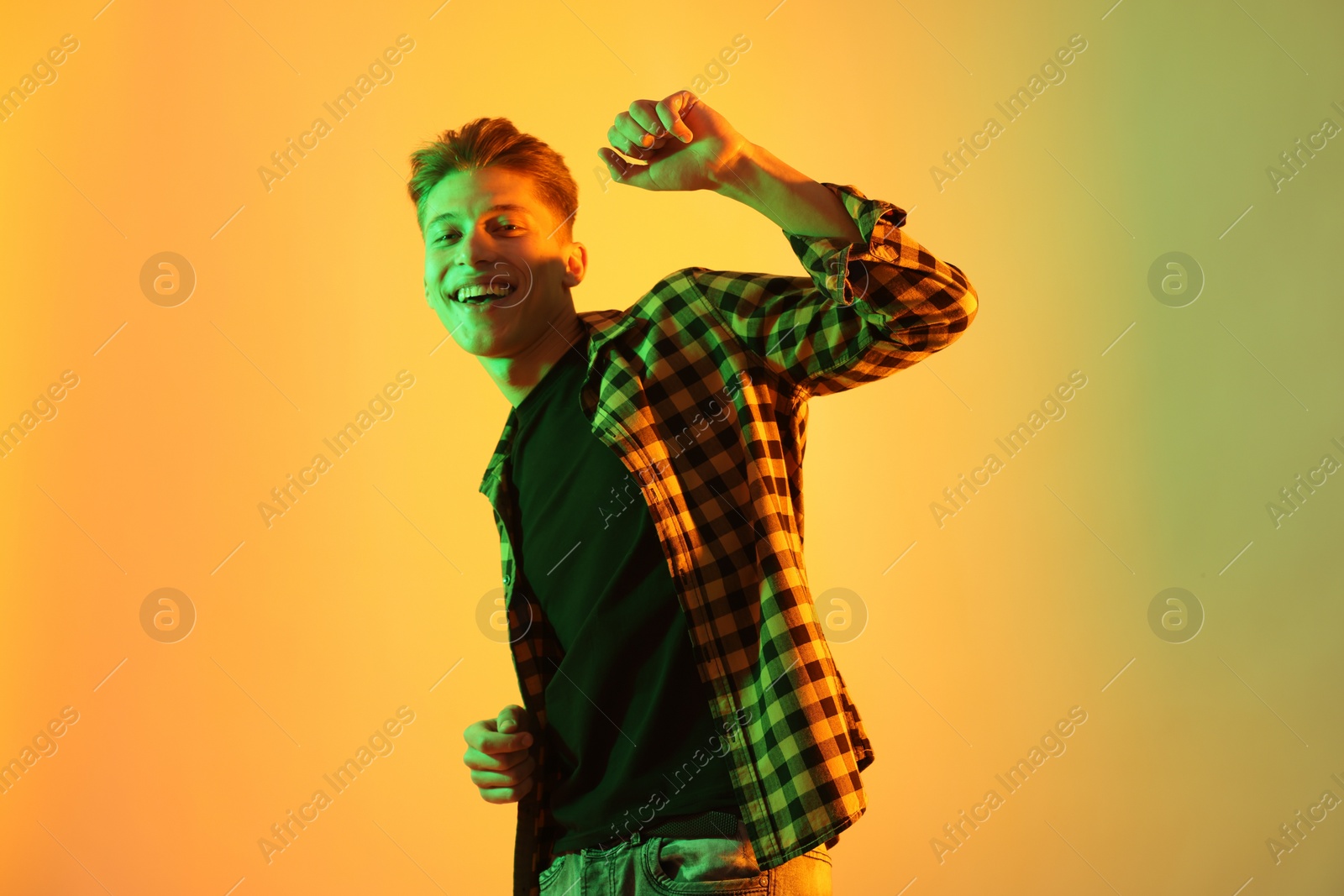 Photo of Young man dancing on color background in neon lights