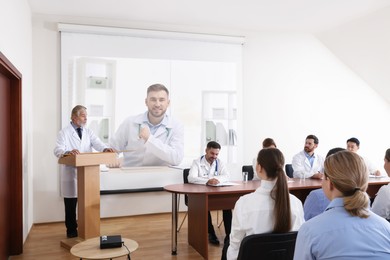Image of Lecture with online participant. Doctors in meeting room. Using projector for videoconference