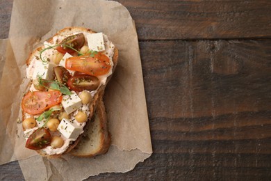 Tasty vegan sandwich with tomatoes, tofu and chickpeas on wooden table, top view. Space for text