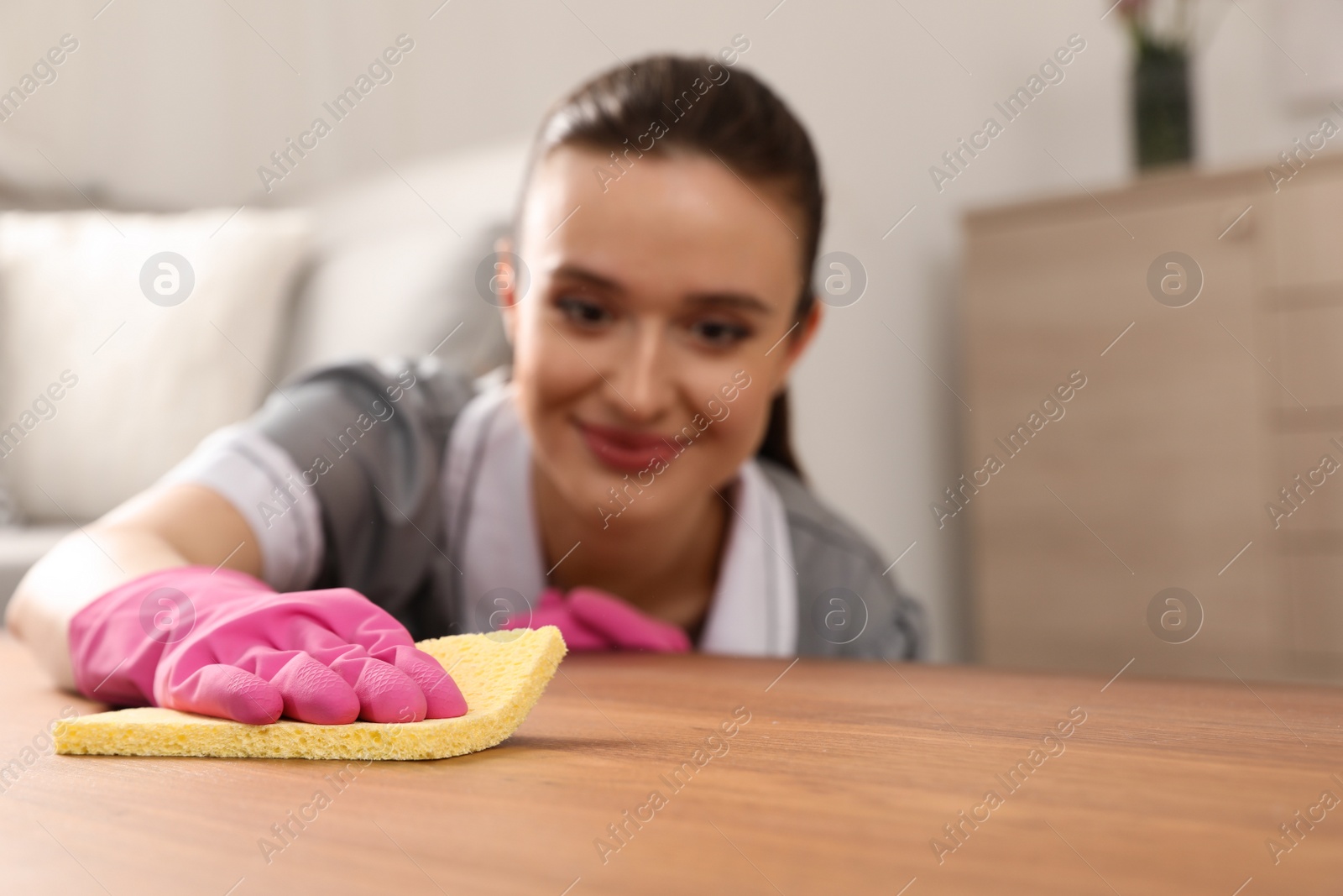 Photo of Young chambermaid wiping dust from table in hotel room, closeup. Space for text