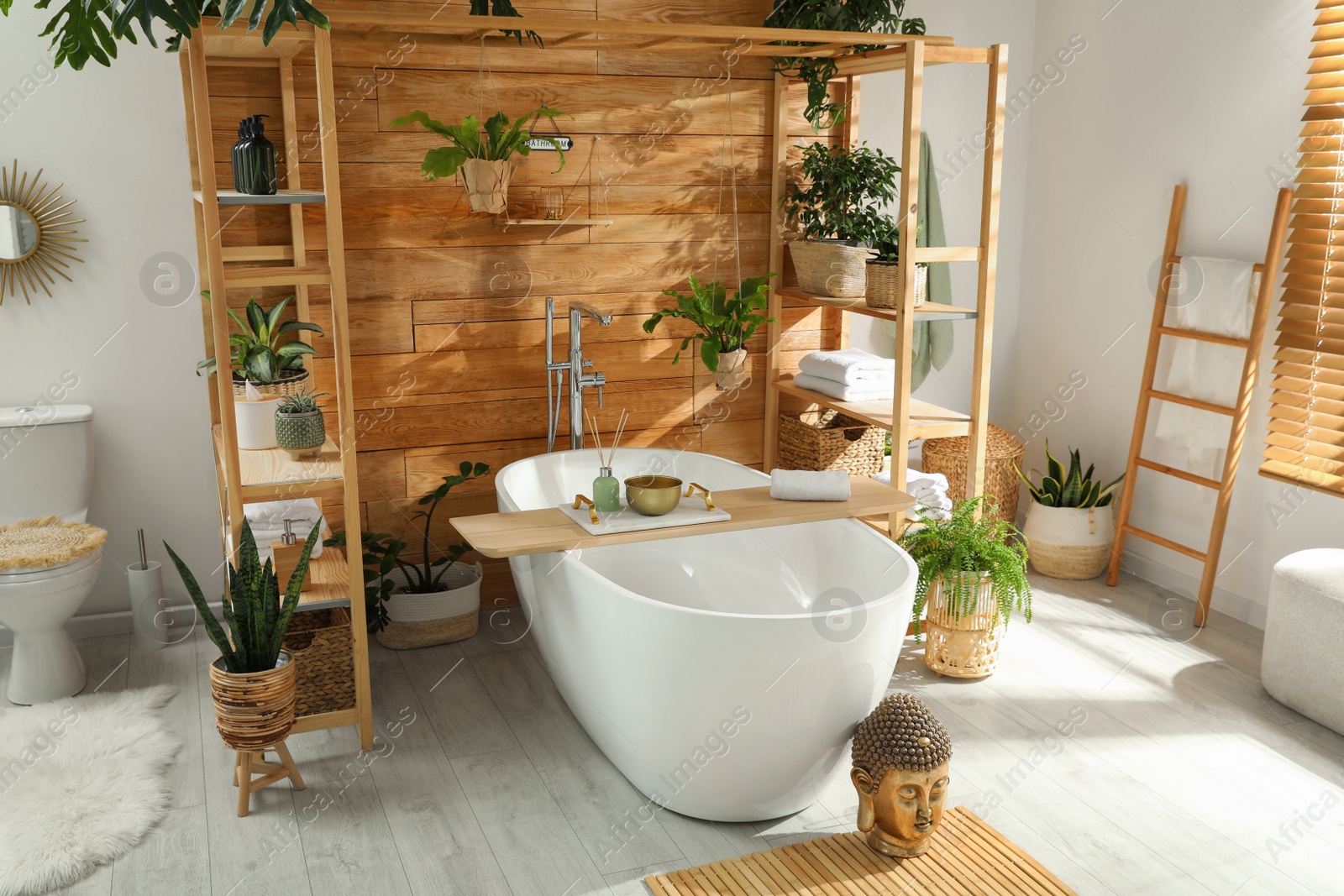 Photo of Stylish bathroom interior with white tub and green houseplants near wooden wall. Idea for design