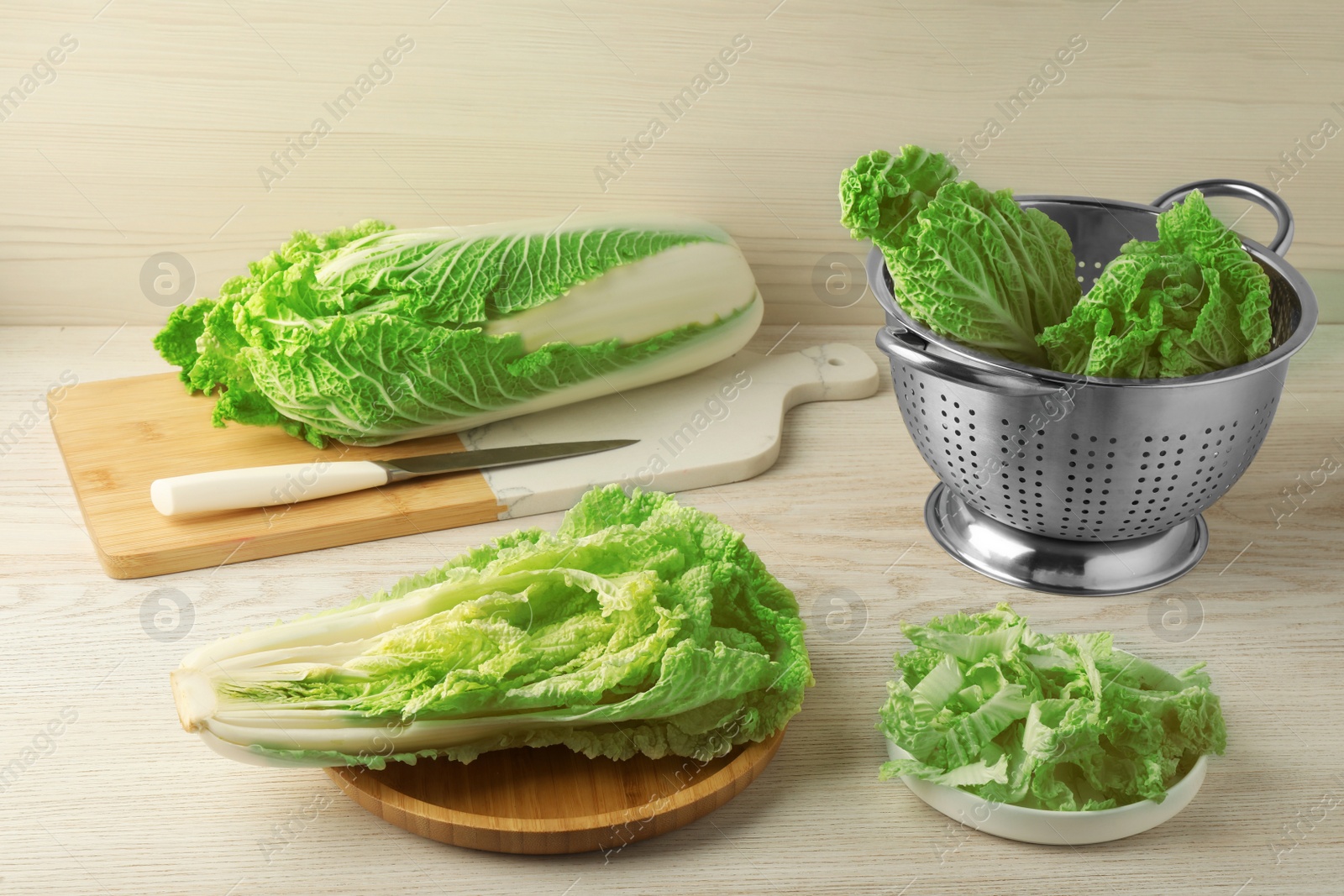 Photo of Whole and cut fresh ripe Chinese cabbages on white wooden table