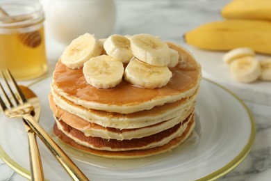 Photo of Delicious pancakes with bananas and honey on white marble table, closeup