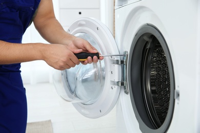 Young handyman fixing washing machine, closeup. Laundry day