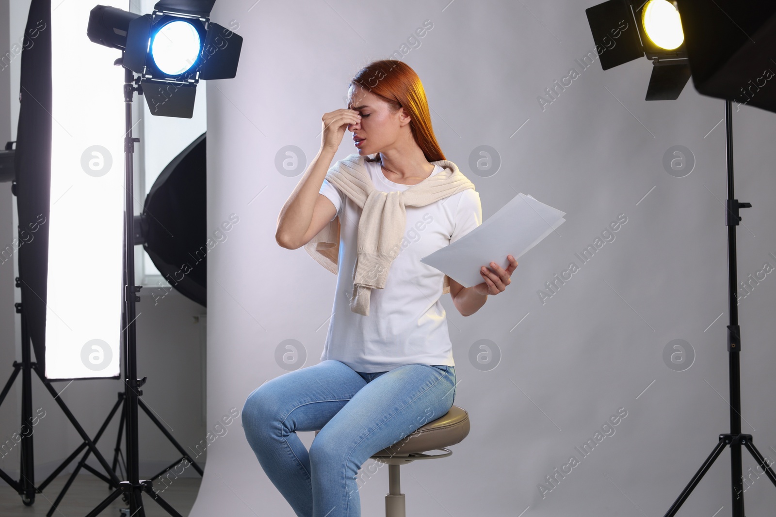 Photo of Casting call. Emotional woman with script performing on grey background in modern studio