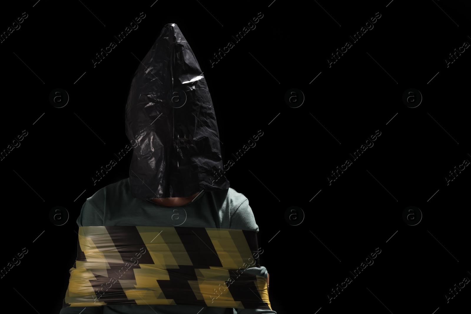 Photo of Little boy in plastic bag tied up and taken hostage on dark background. Space for text