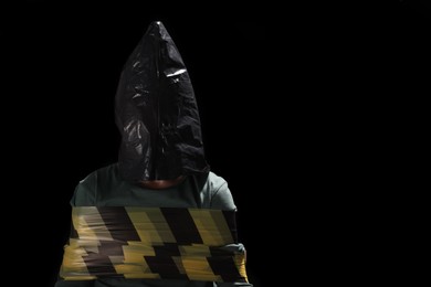 Little boy in plastic bag tied up and taken hostage on dark background. Space for text
