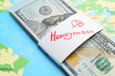 Photo of Stack of money with word Honeymoon on world map, closeup