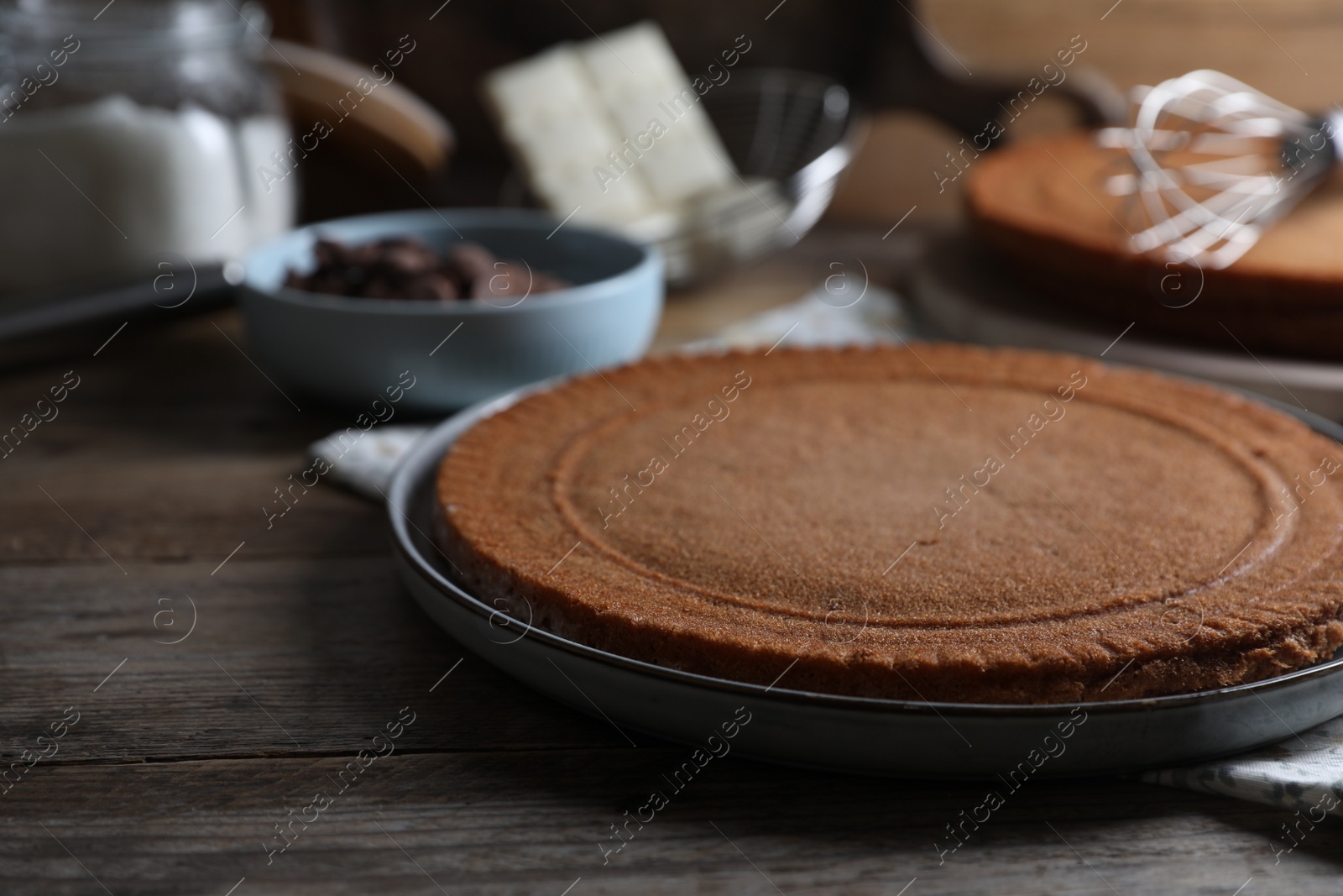 Photo of Delicious homemade sponge cake and ingredients on wooden table, closeup
