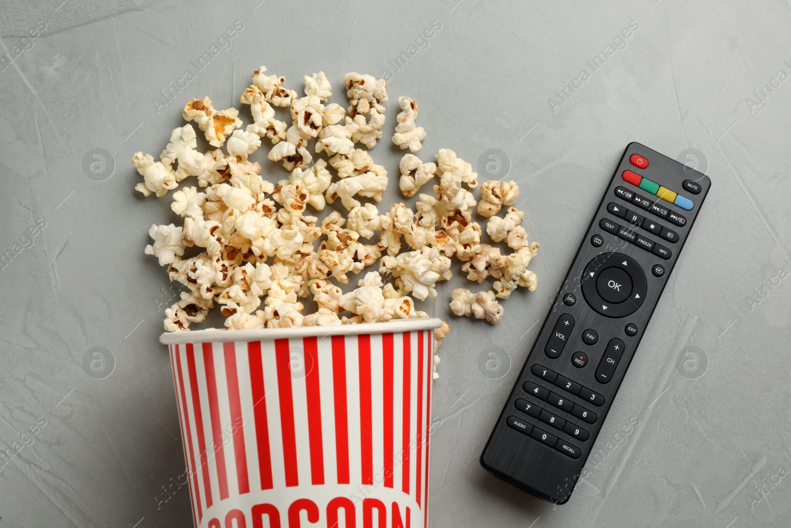 Photo of Modern tv remote control and popcorn on grey table, flat lay