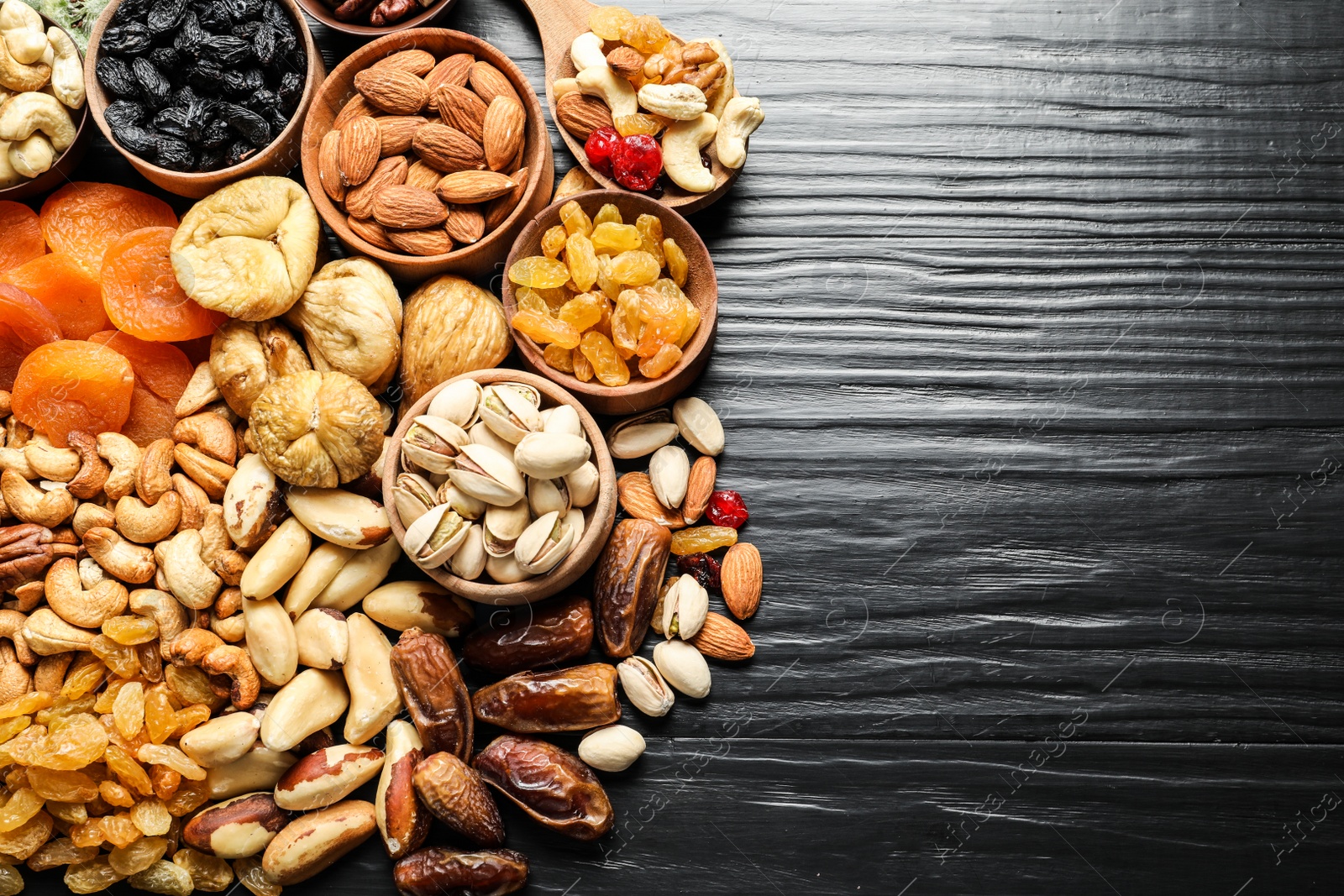 Photo of Flat lay composition of different dried fruits and nuts on color wooden background. Space for text