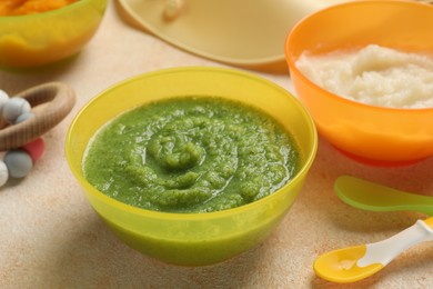 Photo of Baby food. Different tasty puree in bowls on beige textured table, closeup