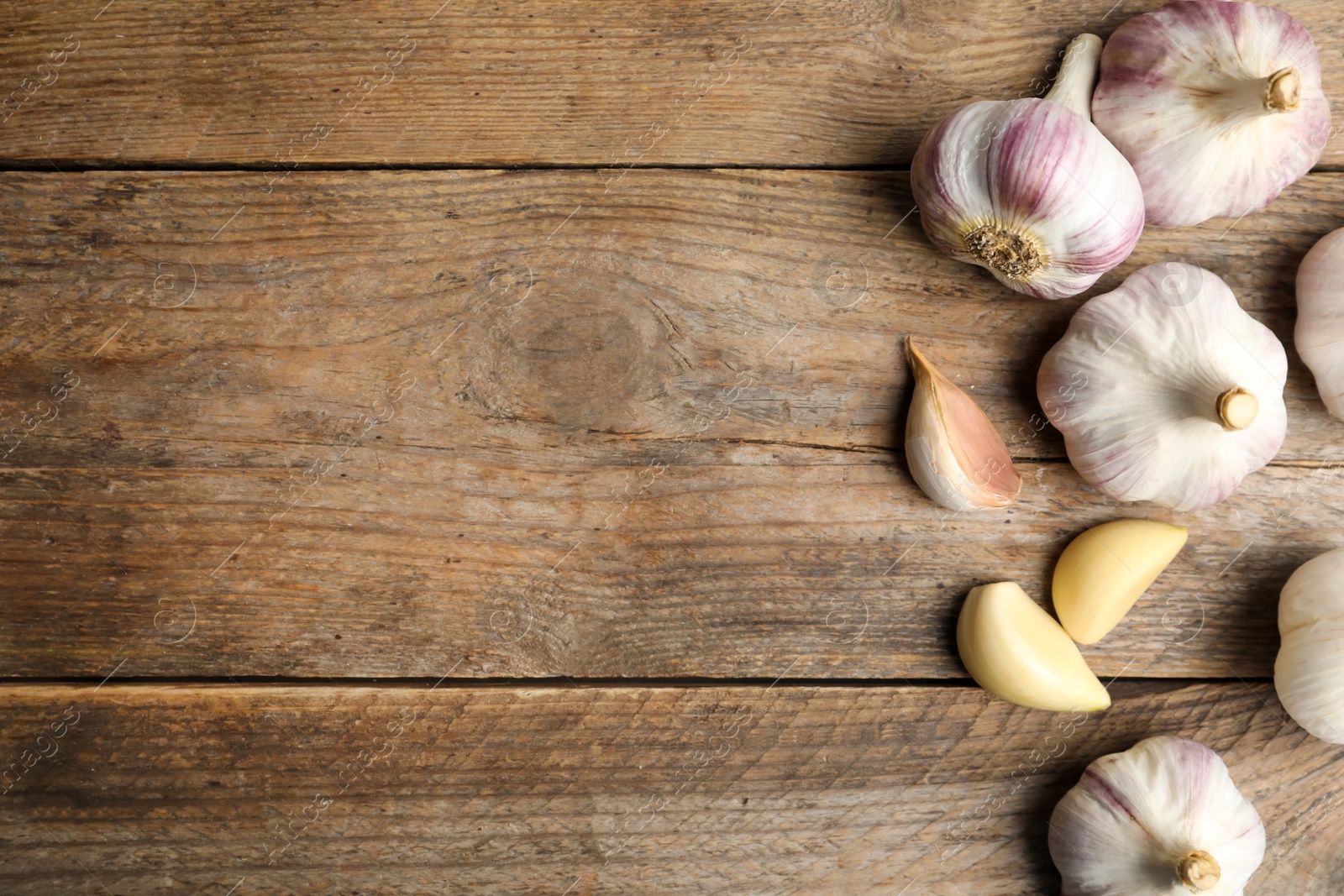 Photo of Fresh organic garlic on wooden table, flat lay. Space for text