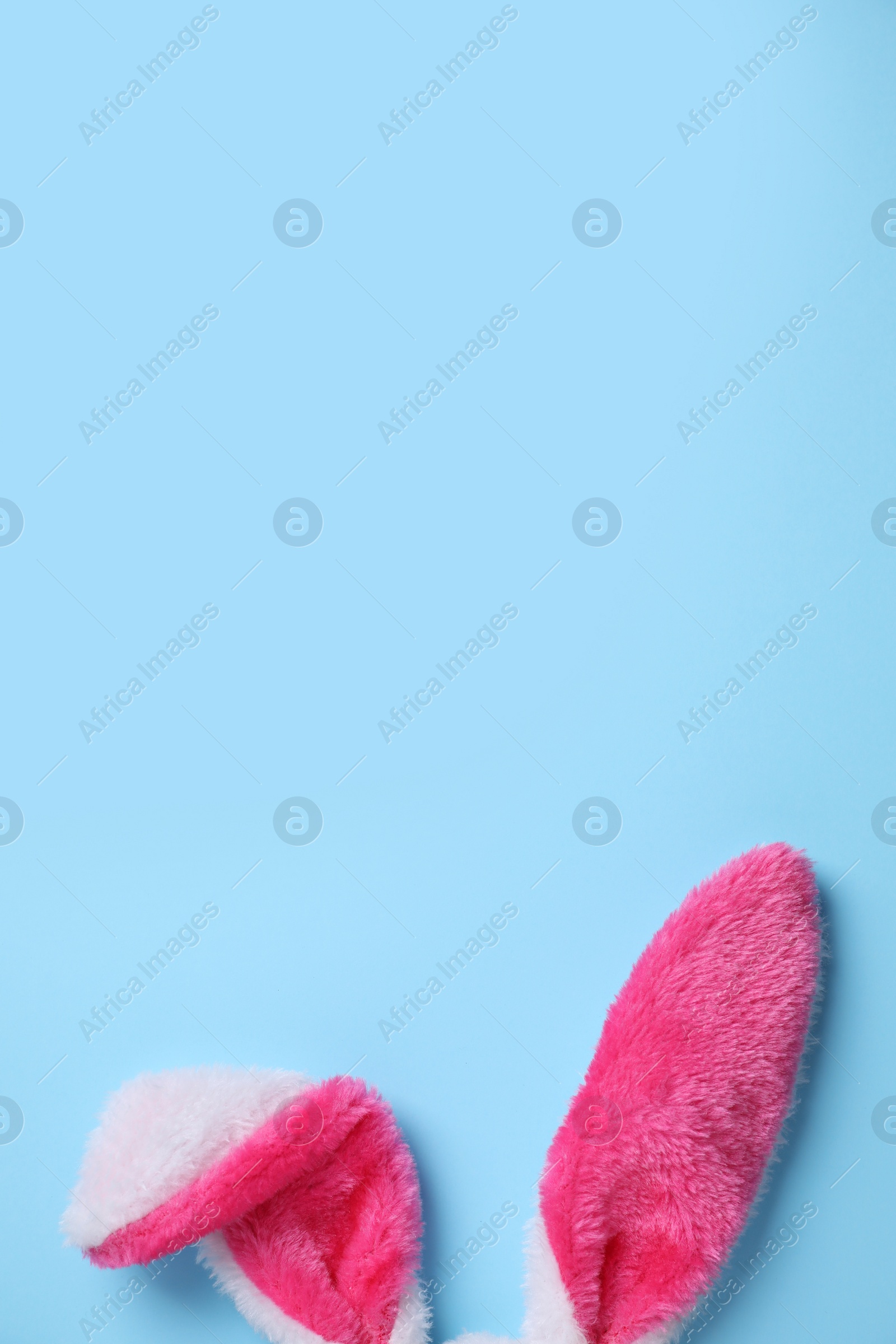 Photo of Decorative bunny ears and space for text on light blue background, flat lay. Easter holiday