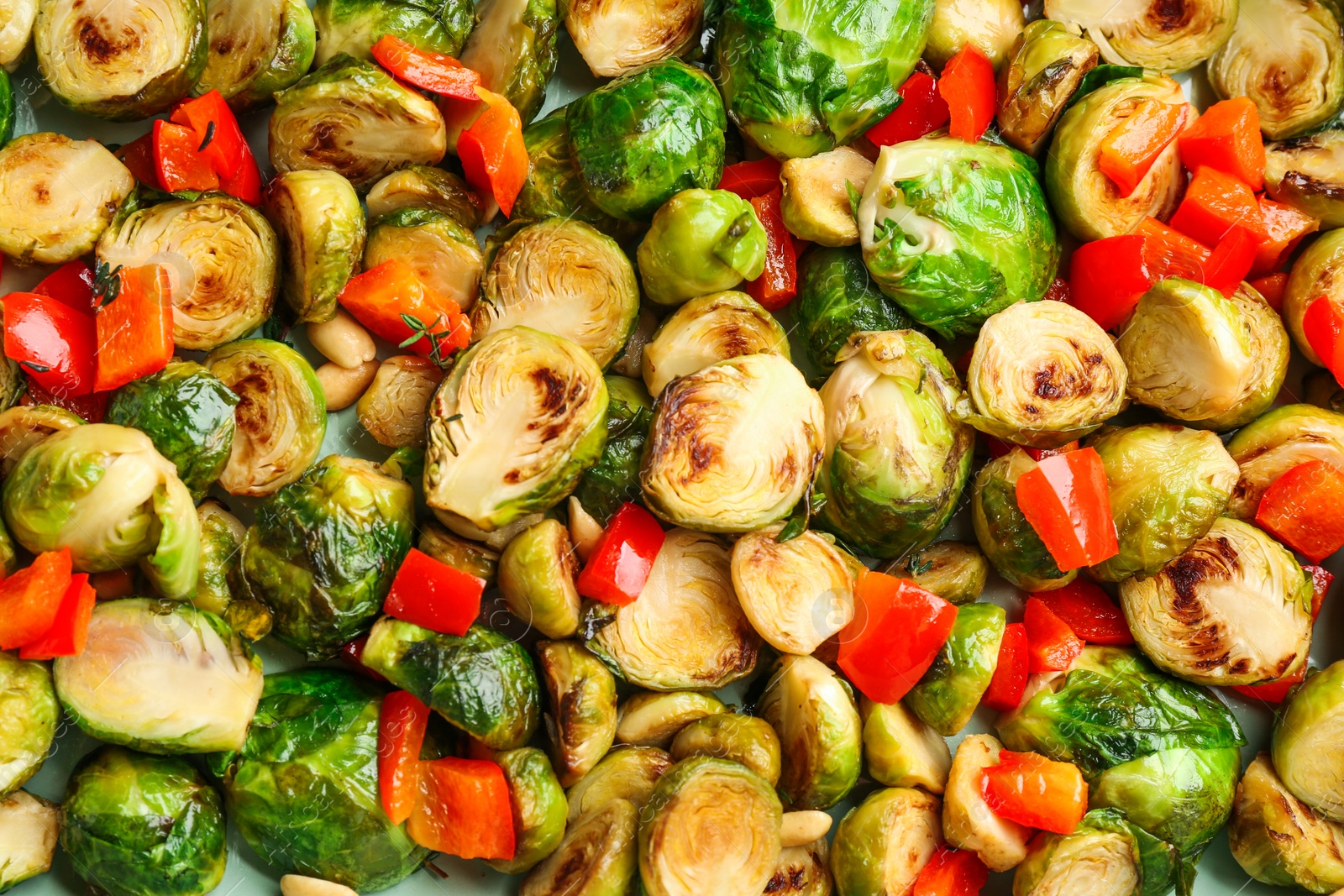Photo of Delicious roasted brussels sprouts with bell pepper and peanuts as background, closeup