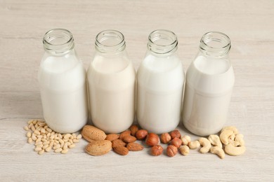 Photo of Different nut milks on white wooden table