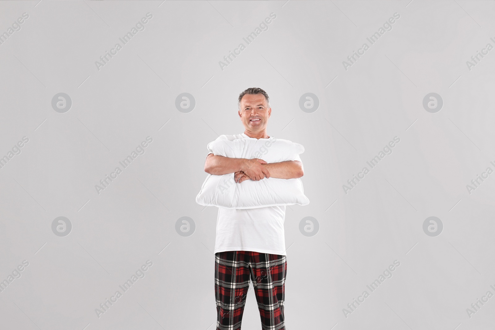 Photo of Man holding soft pillow on light background