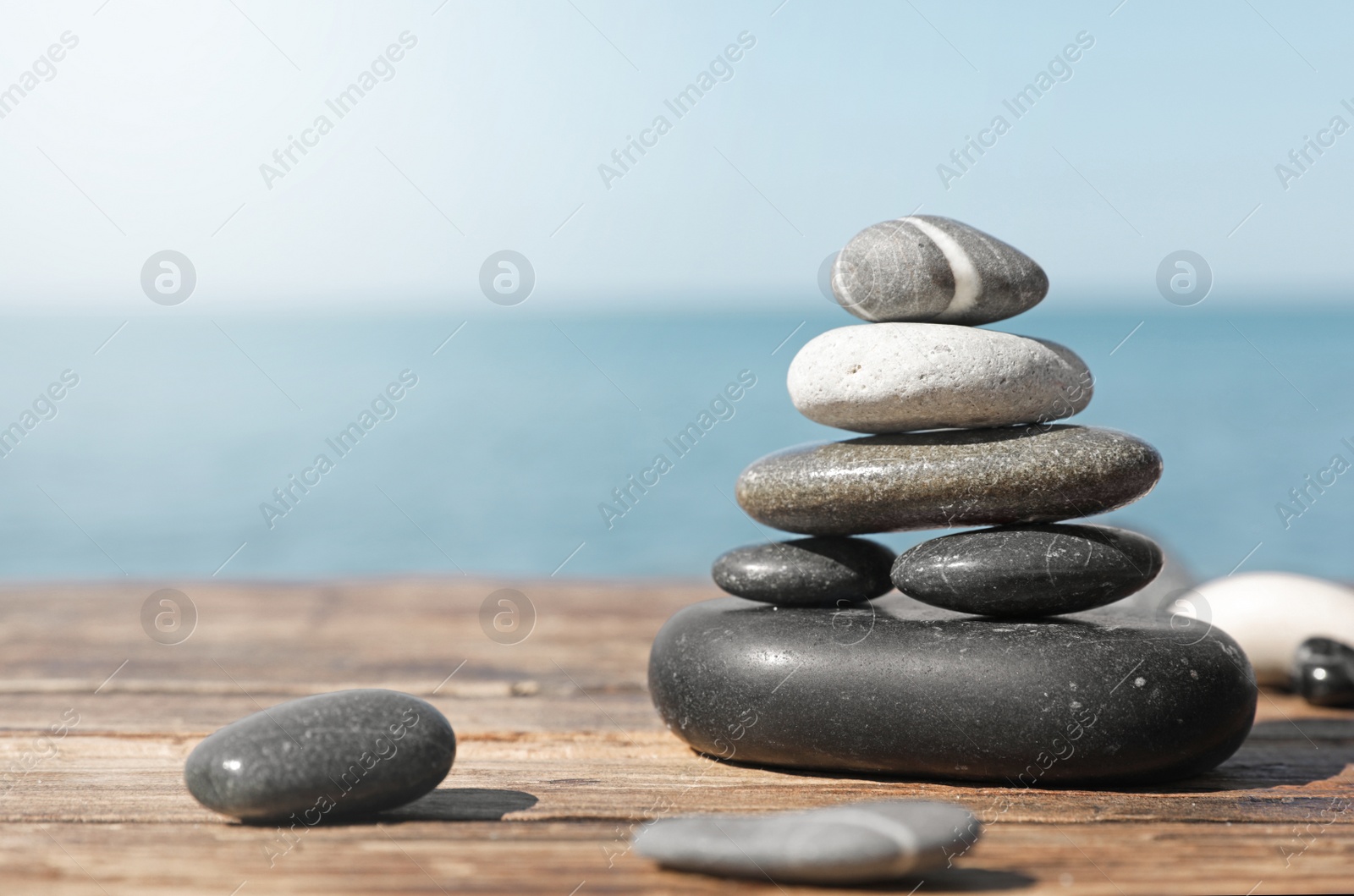 Photo of Stack of stones on wooden pier near sea seascape, space for text. Zen concept