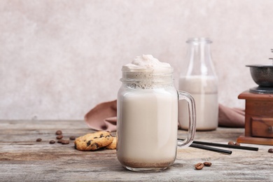 Photo of Mason jar with delicious milk shake on wooden table