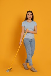 Photo of Beautiful young woman with broom on yellow background