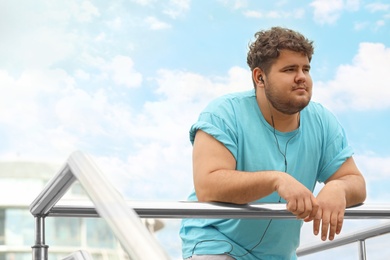Photo of Young overweight man leaning on railing outdoors