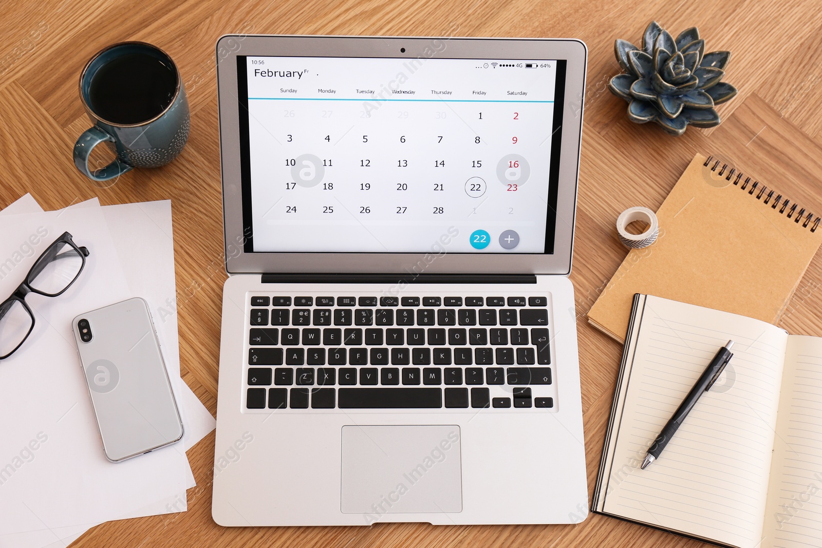 Photo of Modern laptop with calendar on wooden table, above view