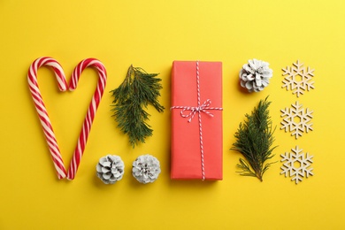 Flat lay composition with candy canes and Christmas decor on yellow background