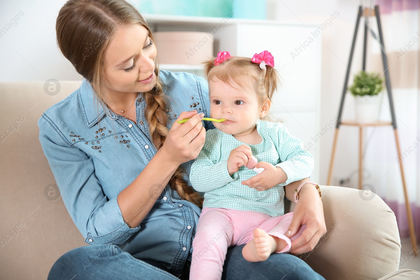 Photo of Caring mother feeding her cute little baby with healthy food at home