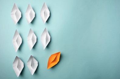 Photo of Yellow paper boat floating away from others on light background, flat lay with space for text. Uniqueness concept