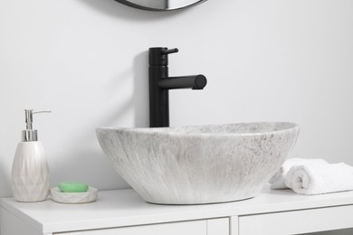 Different bath accessories and personal care products near sink on bathroom vanity