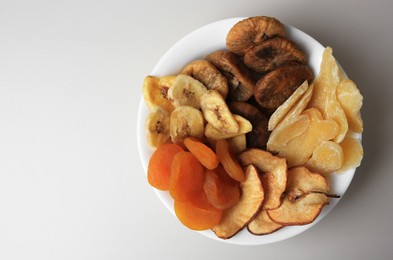 Bowl of different dried fruits on white background, top view. Space for text