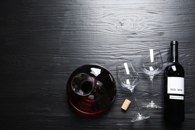 Photo of Decanter, glasses and bottle with red wine on wooden background, flat lay. Space for text