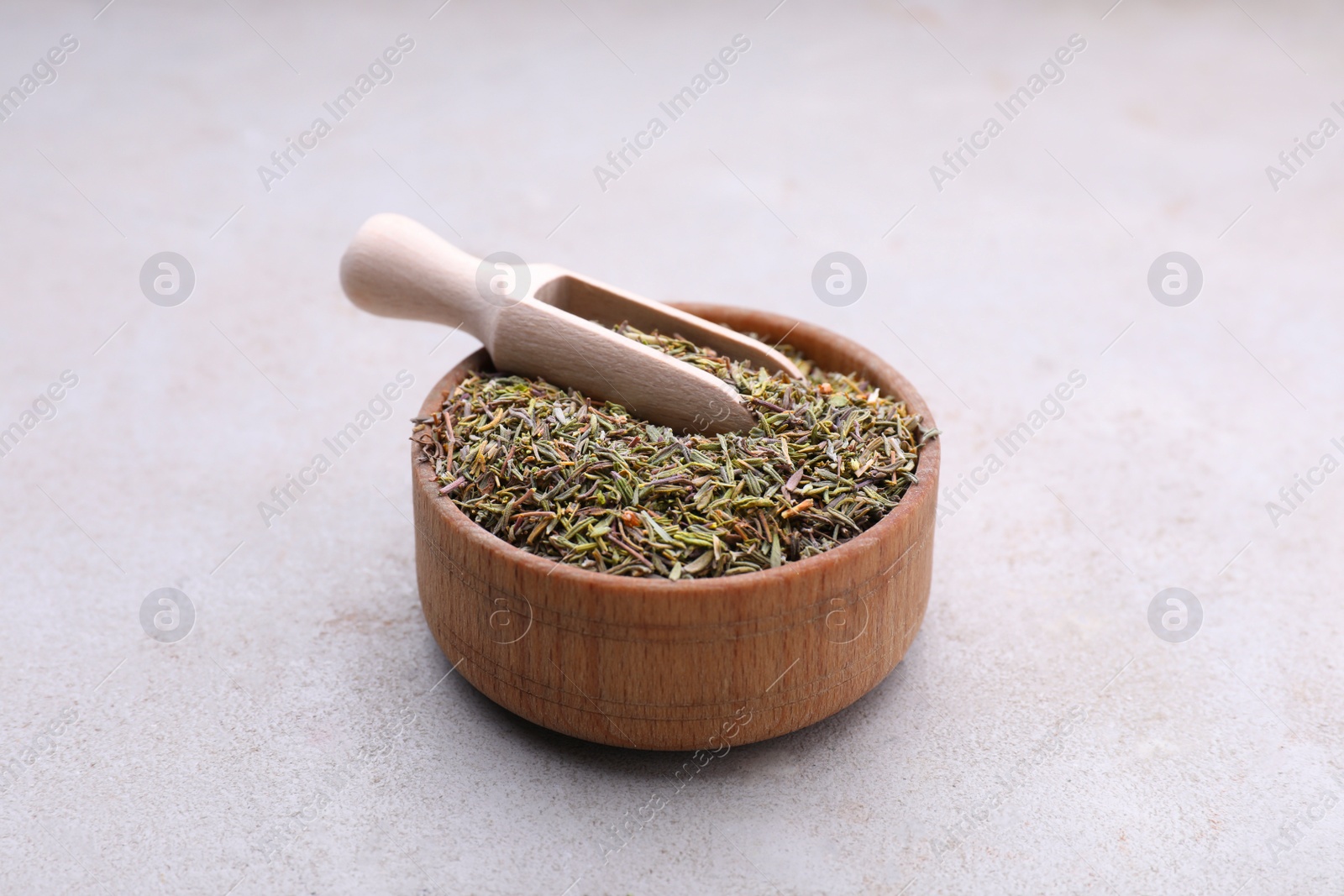 Photo of Bowl and scoop with dried thyme on grey table, closeup