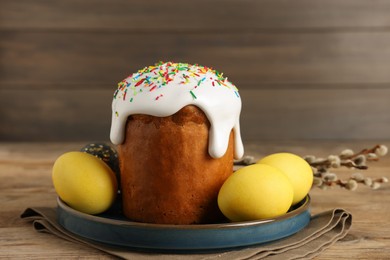 Photo of Tasty Easter cake, decorated eggs and willow branches on wooden table