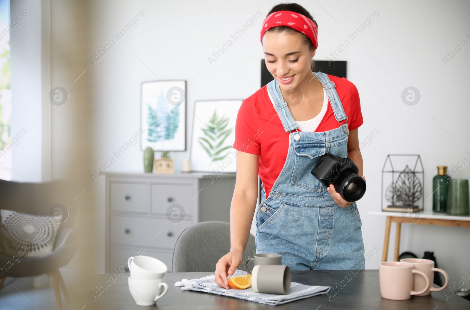 Photo of Young photographer taking picture of cups at table indoors