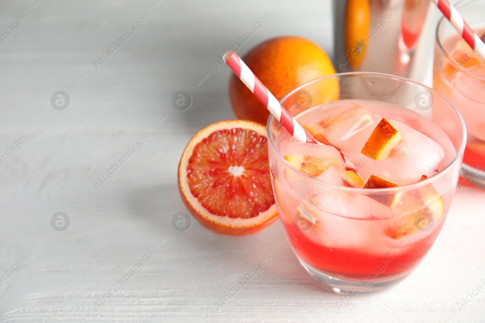 Photo of Glass of tropical cocktail with ice cubes on wooden table. Space for text