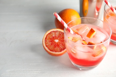 Photo of Glass of tropical cocktail with ice cubes on wooden table. Space for text