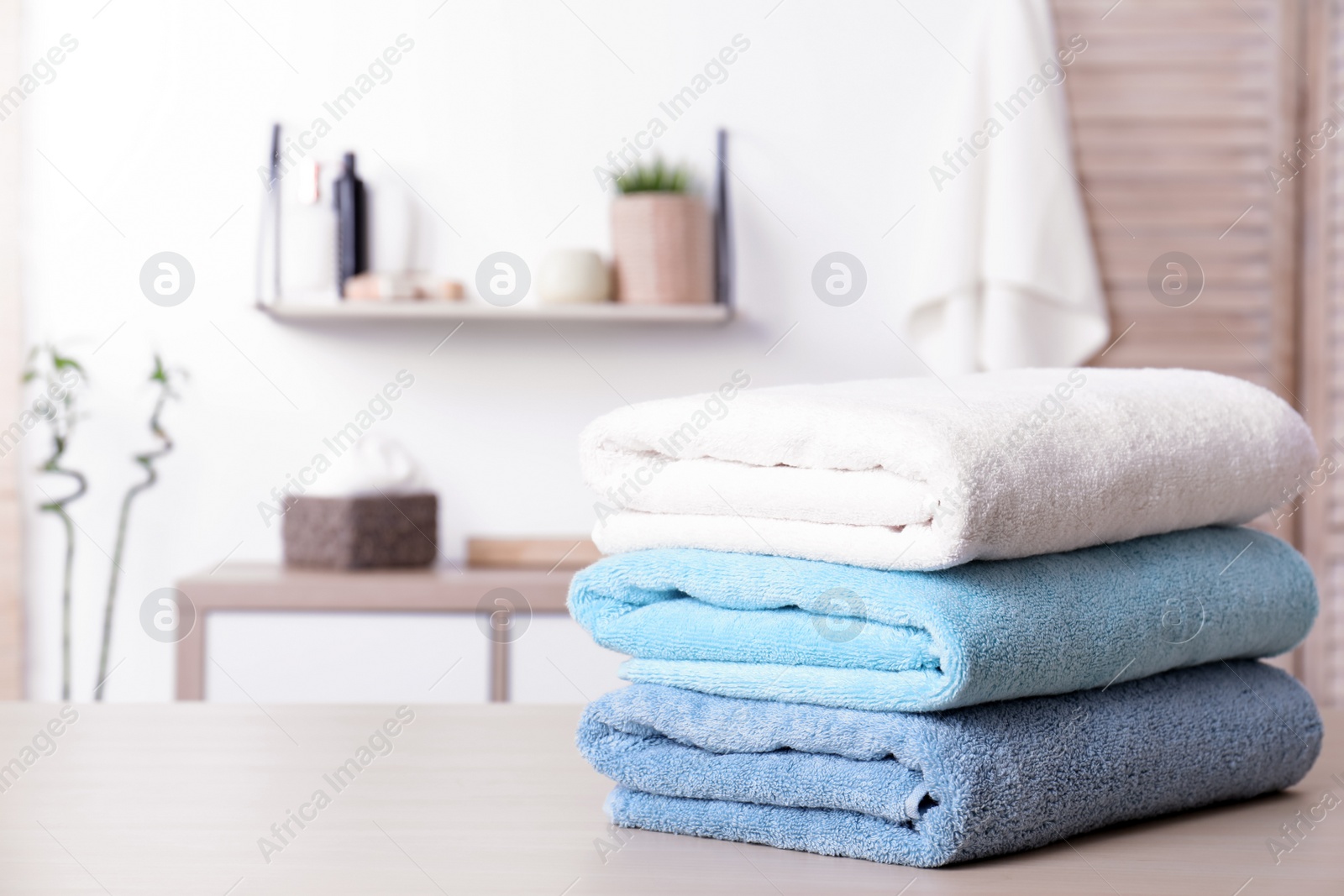 Photo of Stack of fresh towels on table in bathroom. Space for text