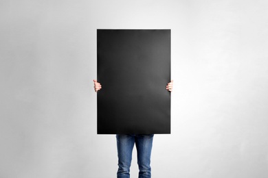 Photo of Man holding blank poster on light grey background